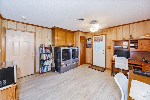 laundry room featuring ceiling fan, light wood-type flooring, wooden walls, washer and clothes dryer, and ornamental molding