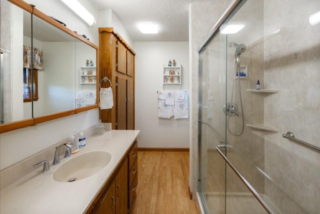 bathroom featuring a textured ceiling, vanity, wood-type flooring, and an enclosed shower