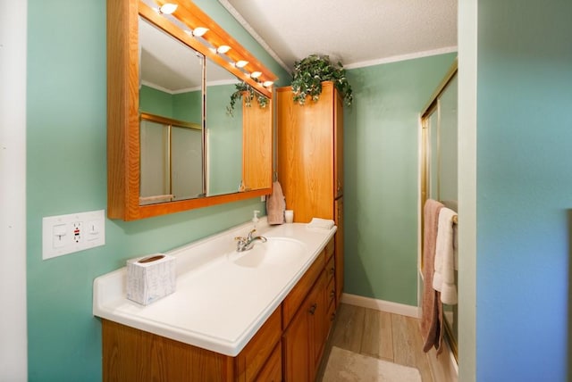 bathroom featuring wood-type flooring, vanity, walk in shower, and crown molding