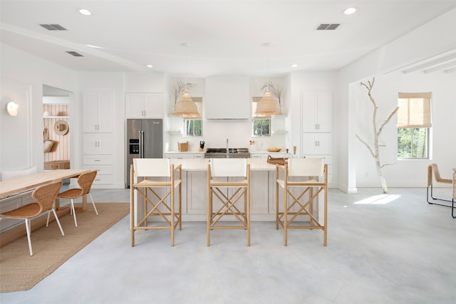 kitchen featuring white cabinets, a breakfast bar, a kitchen island, and high end refrigerator