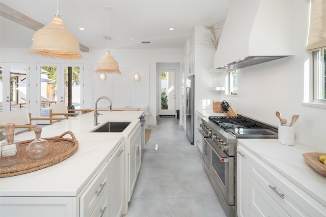 kitchen with exhaust hood, sink, appliances with stainless steel finishes, decorative light fixtures, and white cabinetry