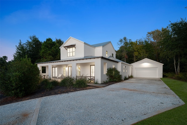 view of front of property featuring covered porch, an outdoor structure, and a garage