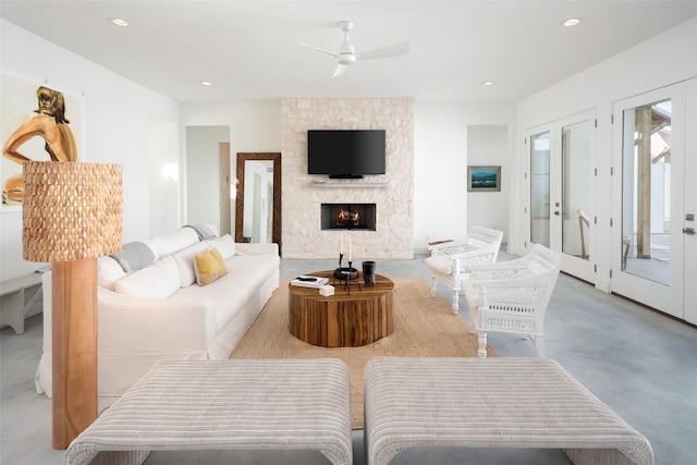 living room with a stone fireplace and ceiling fan