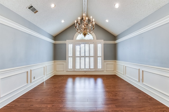 empty room featuring vaulted ceiling, a textured ceiling, dark hardwood / wood-style floors, and an inviting chandelier