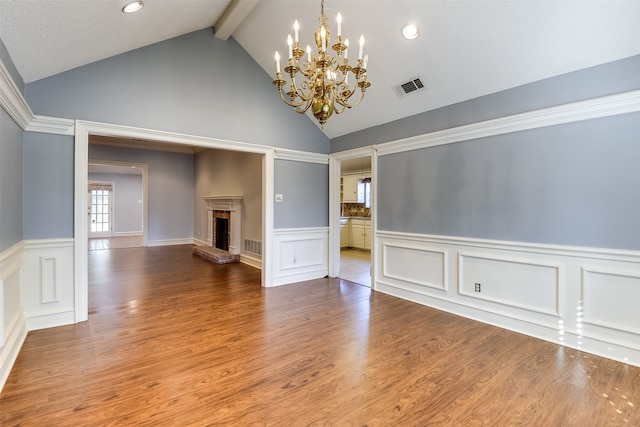 unfurnished living room with a fireplace, wood-type flooring, lofted ceiling with beams, and a chandelier