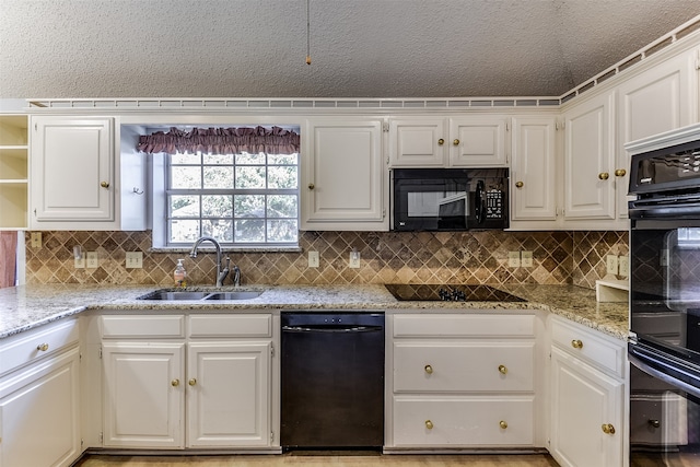 kitchen featuring black appliances, light stone countertops, white cabinetry, and sink