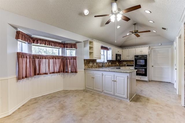 kitchen featuring kitchen peninsula, backsplash, black appliances, white cabinetry, and lofted ceiling