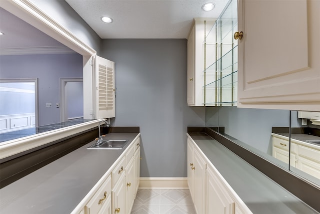 kitchen featuring white cabinetry, ornamental molding, and sink