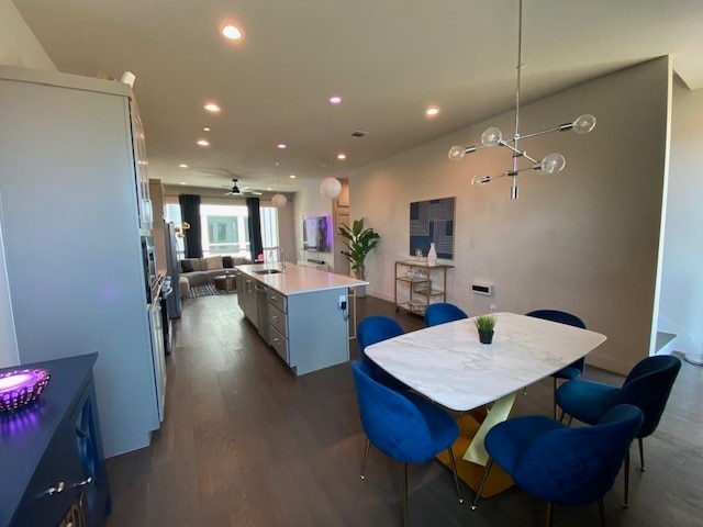 dining room featuring ceiling fan, sink, and dark wood-type flooring