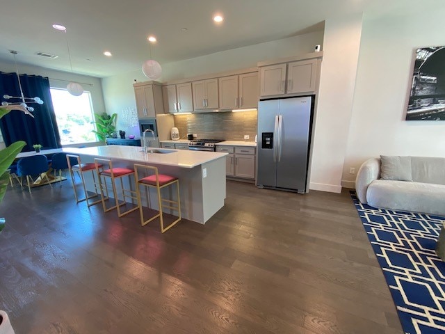 kitchen featuring sink, dark hardwood / wood-style flooring, stainless steel appliances, and an island with sink