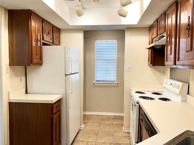 kitchen with a raised ceiling, white appliances, and rail lighting