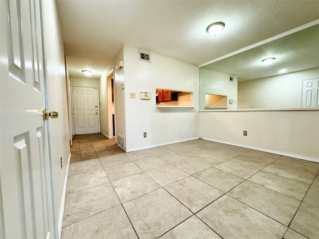 tiled empty room featuring a textured ceiling