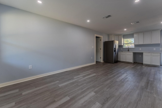 kitchen featuring white cabinetry, stainless steel fridge, sink, and wood-type flooring