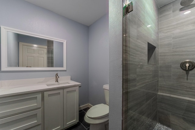 bathroom featuring a tile shower, vanity, and toilet