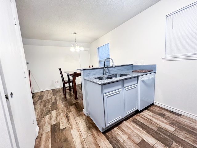 kitchen with sink, hanging light fixtures, stainless steel dishwasher, dark hardwood / wood-style flooring, and kitchen peninsula