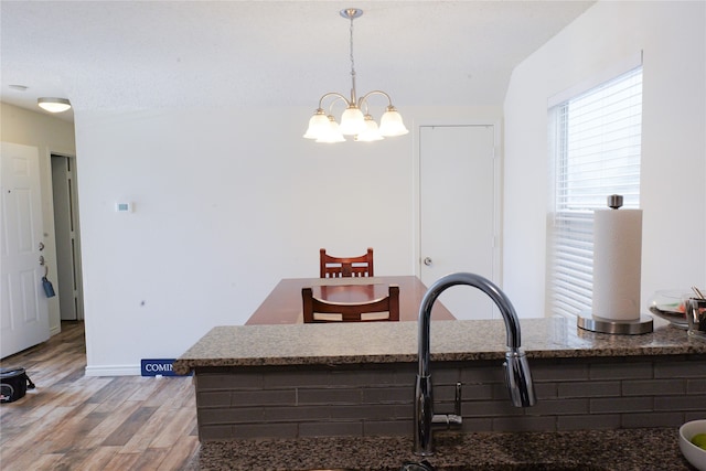 kitchen with sink, hanging light fixtures, light hardwood / wood-style flooring, a textured ceiling, and a chandelier