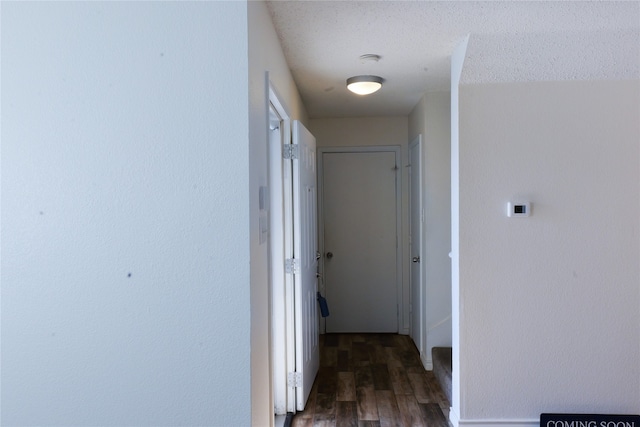 hallway featuring dark wood-type flooring and a textured ceiling