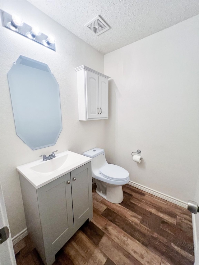 bathroom with vanity, hardwood / wood-style floors, a textured ceiling, and toilet