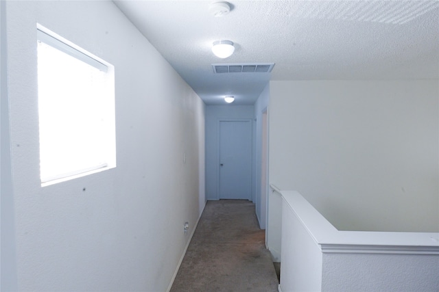 hall with carpet floors and a textured ceiling