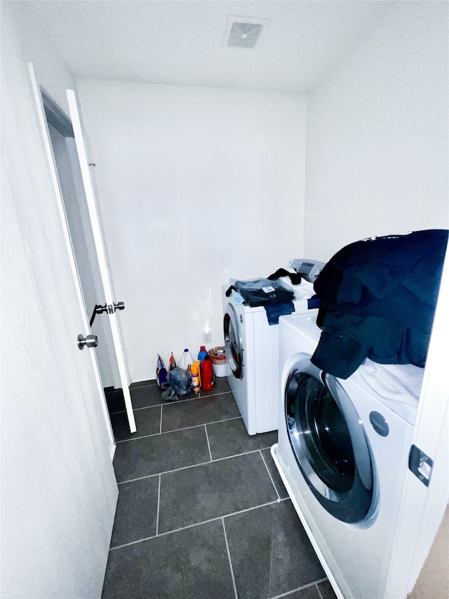 laundry room with dark tile patterned flooring and washing machine and dryer