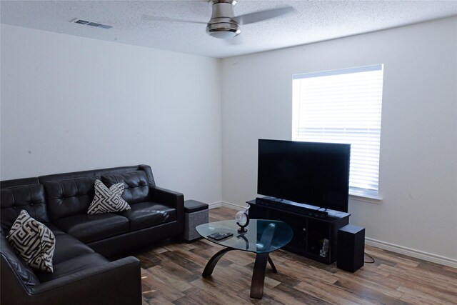 living room with ceiling fan, a textured ceiling, and hardwood / wood-style flooring