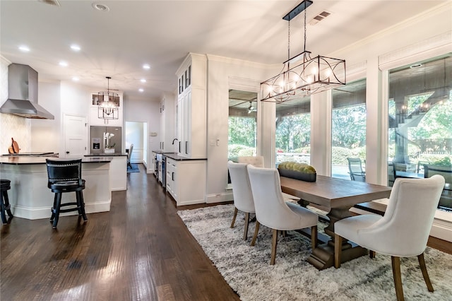 dining room featuring crown molding, sink, dark wood-type flooring, and an inviting chandelier