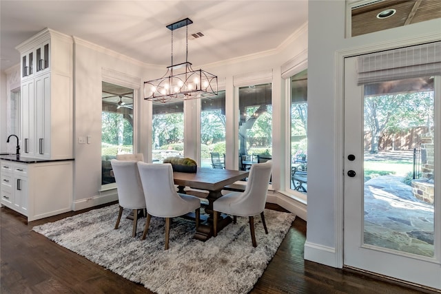 dining space featuring crown molding, dark wood-type flooring, and a notable chandelier