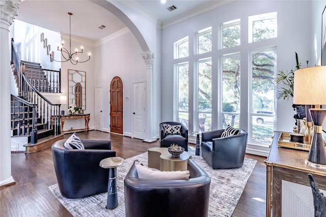 living room featuring crown molding, dark hardwood / wood-style flooring, a towering ceiling, and an inviting chandelier