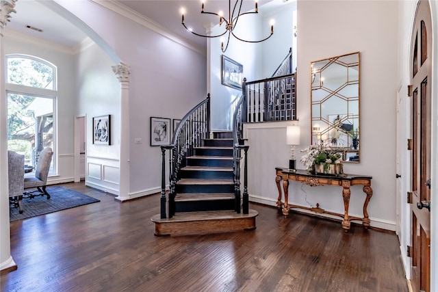 entryway with dark hardwood / wood-style flooring, ornamental molding, a high ceiling, and an inviting chandelier