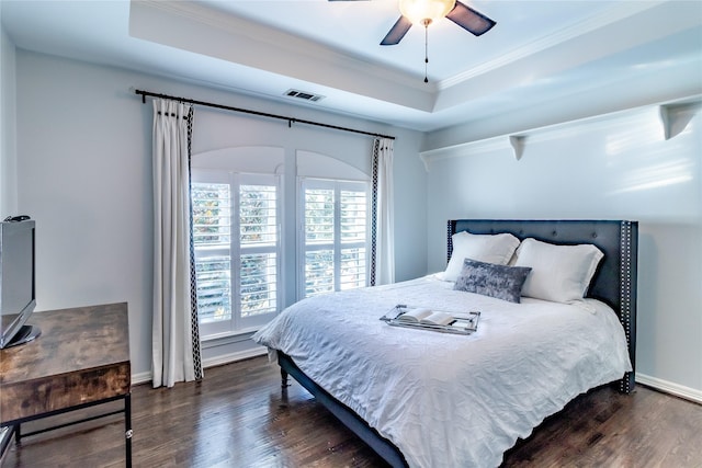 bedroom featuring a raised ceiling, crown molding, ceiling fan, and dark wood-type flooring