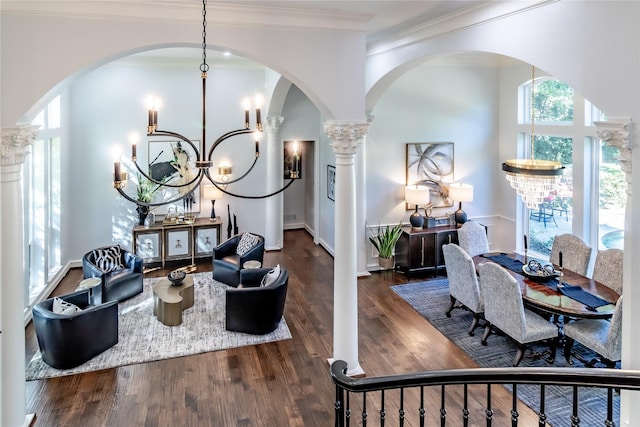 interior space with dark hardwood / wood-style floors, ornate columns, crown molding, and an inviting chandelier