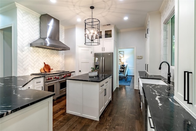 kitchen with white cabinets, appliances with stainless steel finishes, pendant lighting, and wall chimney range hood