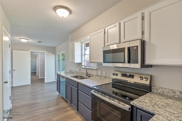 kitchen with white cabinetry, appliances with stainless steel finishes, light stone countertops, and sink