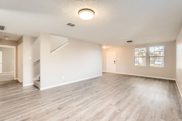 unfurnished room with light wood-type flooring and a textured ceiling