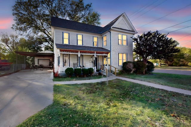 view of front of home with a lawn, a porch, and a carport