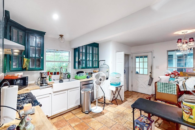 kitchen with white cabinets, gas stovetop, sink, and a chandelier