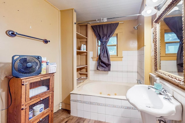 bathroom with hardwood / wood-style floors, a relaxing tiled tub, and sink