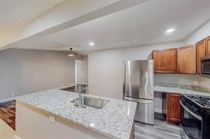 kitchen featuring sink, a kitchen island, light stone countertops, light hardwood / wood-style floors, and stainless steel appliances