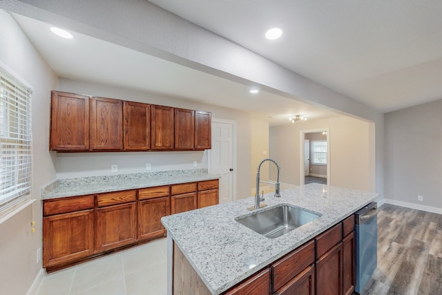 kitchen with recessed lighting, brown cabinetry, a sink, an island with sink, and dishwasher