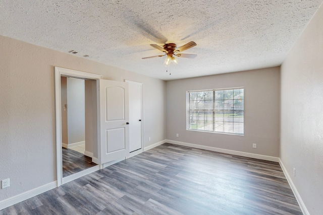 unfurnished bedroom with visible vents, dark wood finished floors, a textured ceiling, and baseboards