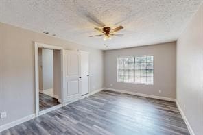 unfurnished bedroom with ceiling fan, dark hardwood / wood-style flooring, and a textured ceiling