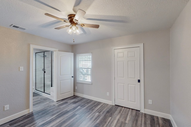 unfurnished bedroom with a textured ceiling, a ceiling fan, visible vents, baseboards, and dark wood finished floors