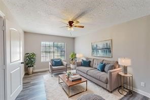 living room with hardwood / wood-style floors, a textured ceiling, and ceiling fan