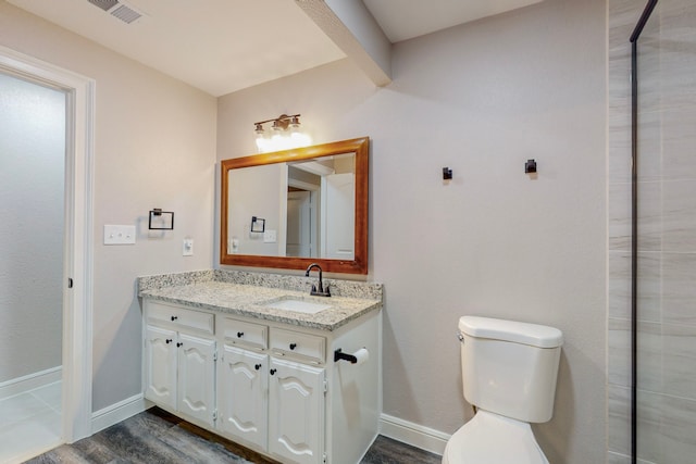 bathroom featuring toilet, wood finished floors, vanity, visible vents, and baseboards