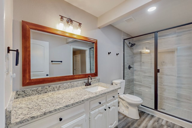 bathroom featuring toilet, a stall shower, wood finished floors, and vanity