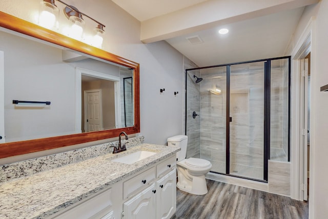 bathroom with toilet, a shower stall, wood finished floors, and vanity