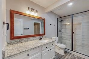 bathroom with hardwood / wood-style floors, vanity, toilet, and a shower with shower door