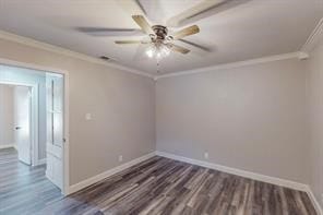 empty room with ornamental molding, ceiling fan, and dark wood-type flooring