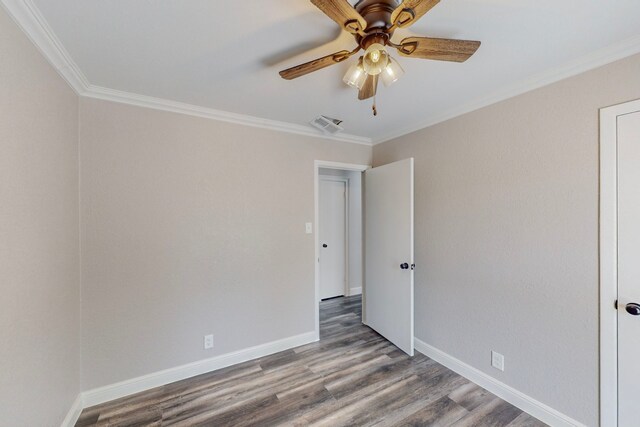 spare room with crown molding, wood finished floors, and baseboards