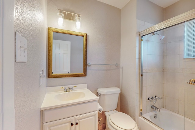 bathroom with a textured wall, shower / bath combination with glass door, vanity, and toilet